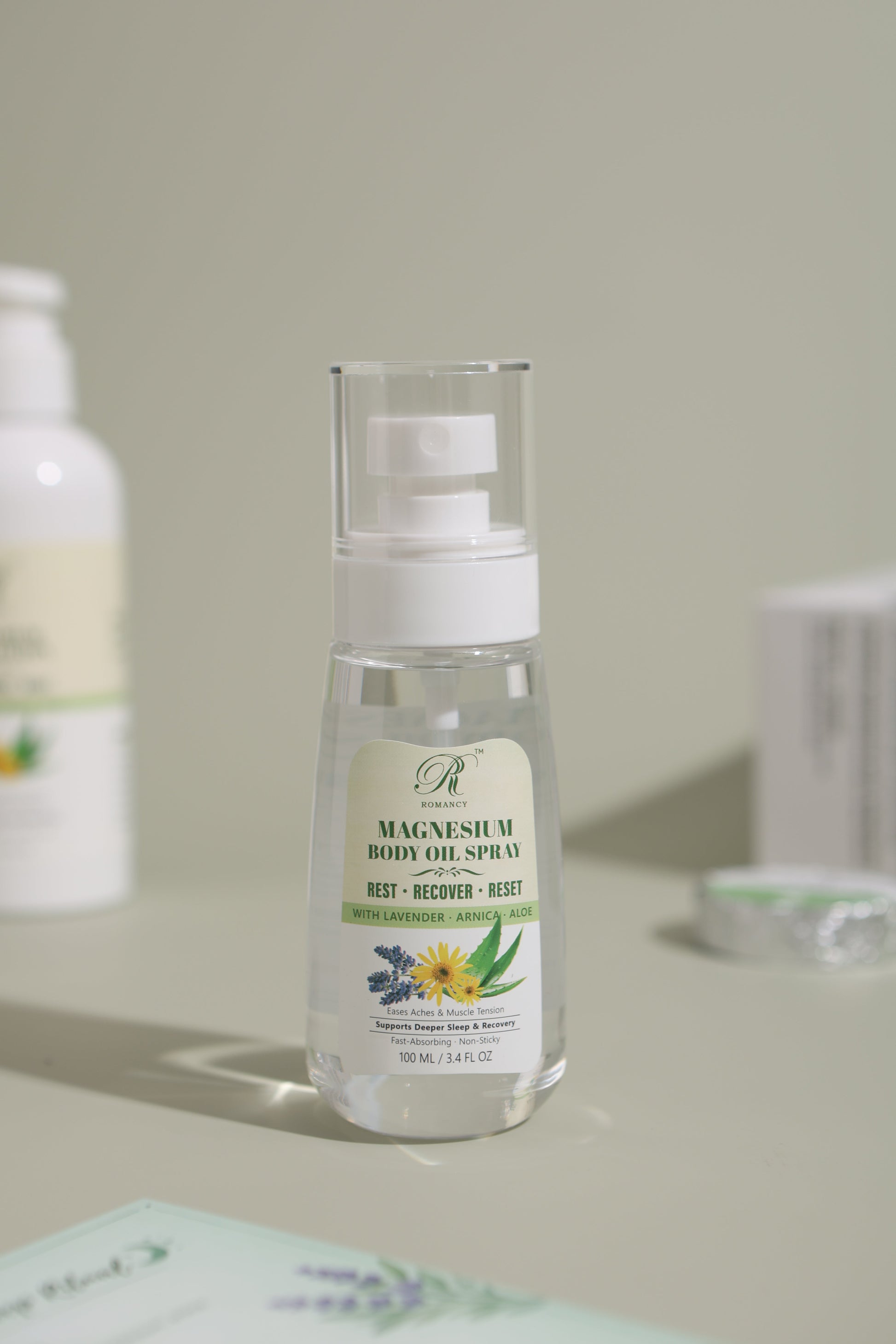 Romancy magnesium body oil in a white pump bottle on a soft green background
