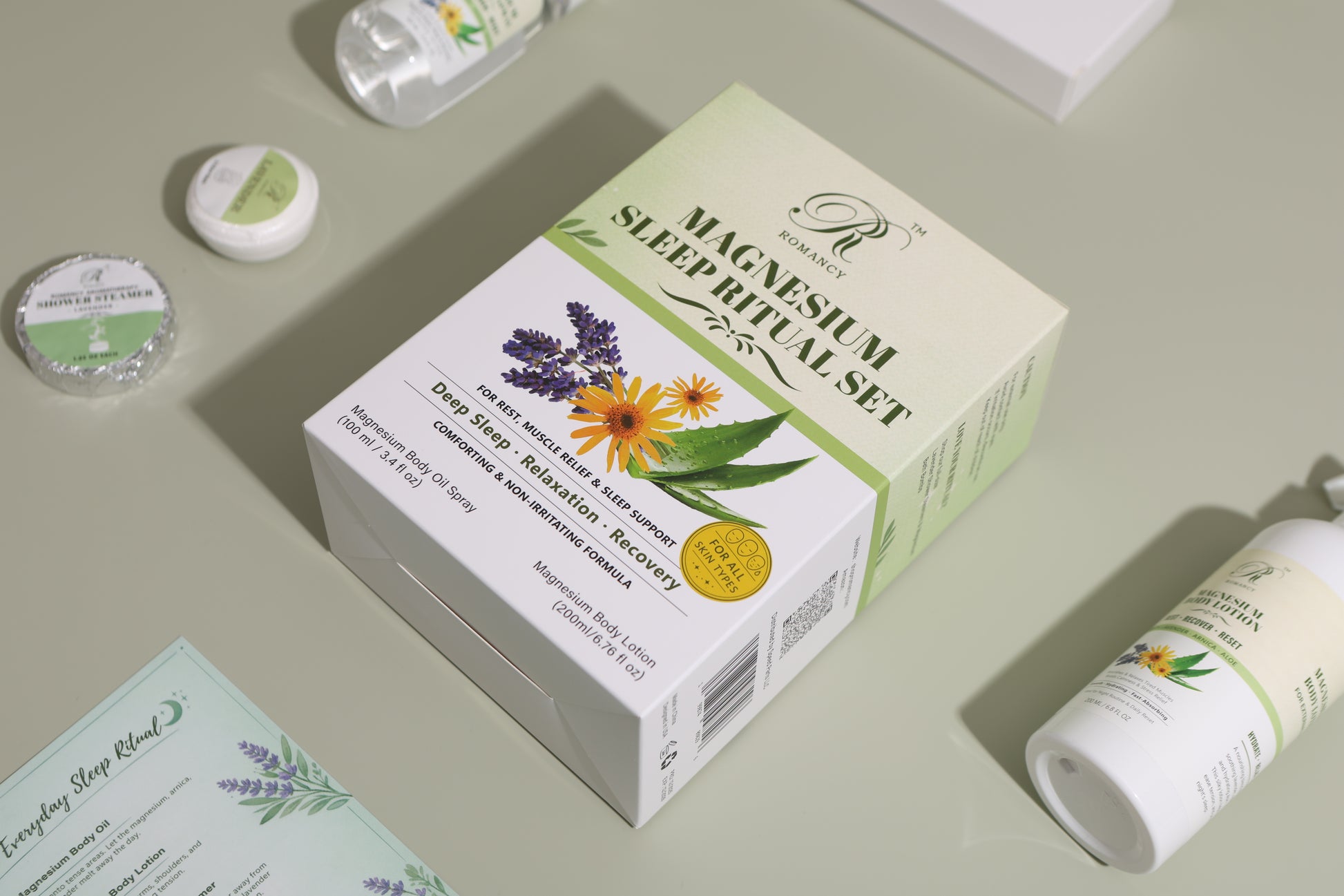 Romancy magnesium sleep ritual set box with botanical design, shown at an angle on a soft green background with included products
